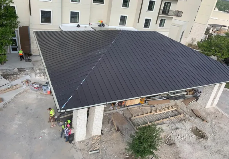 Metal roofing installation team working on a commercial building in Harrisonville